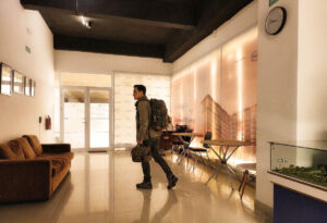 Seorang traveler pria membawa tas backpack melintasi lobi Apartemen Tamansari Skylounge Makassar menuju akses keberangkatan Bandara Sultan Hasanuddin.
